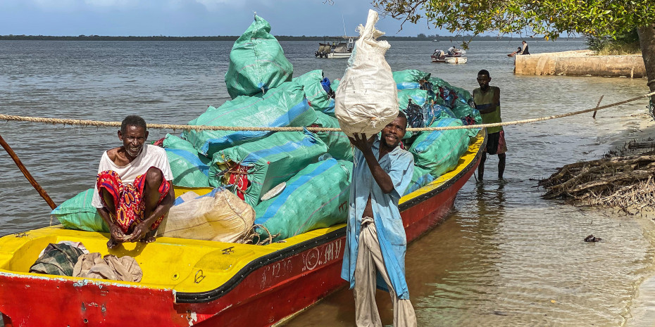 Two waste workers in Lamu, Kenya. with collected plastic on a boat.